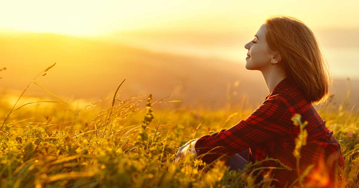 A woman relaxing in a filed as the sun rises in alabama after getting ketamine therapy for her anxiety treatment in birmingham and auburn, al, at southern mind and wellness